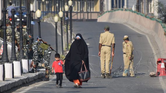 A woman and her child cross the street at a military checkpoint.