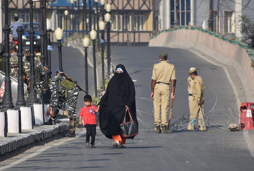 A woman and her child cross the street at a military checkpoint.