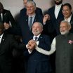 A group of world leaders standing together, smiling, with their hands joined.