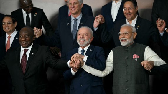 A group of world leaders standing together, smiling, with their hands joined.